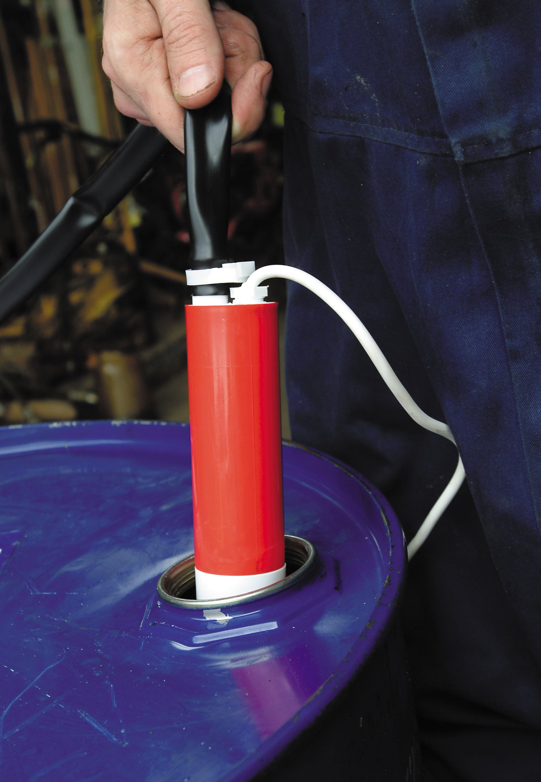 Amazon Low Voltage Pumps - location shot of Amazon transferring water from metal barrel with hose attachment  